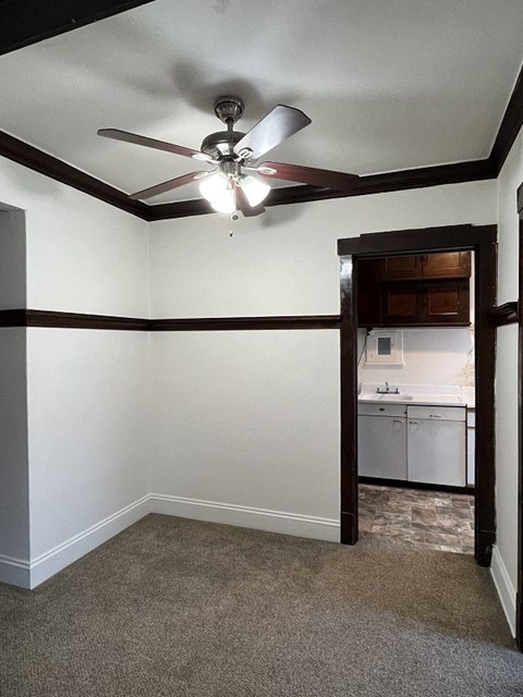 A room with a ceiling fan and a carpeted floor.