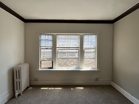 A room with a window and a radiator on the floor.