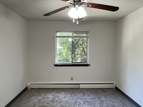 A room with a ceiling fan and a window.