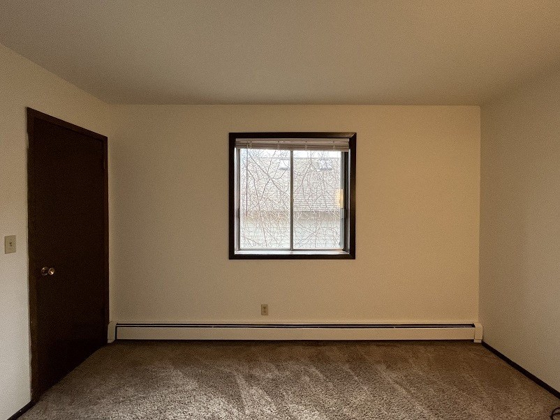 A room with a carpeted floor and a window.