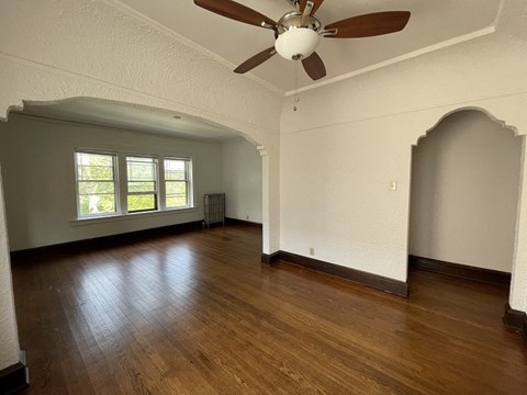 an empty living room with a ceiling fan and hardwood floors