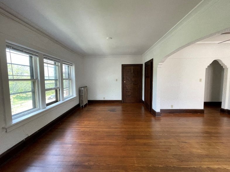 an empty room with hardwood floors and large windows