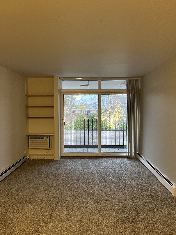 A room with a carpeted floor and a sliding glass door leading outside.