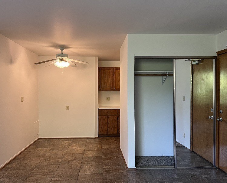 A room with a ceiling fan and a door leading to another room.