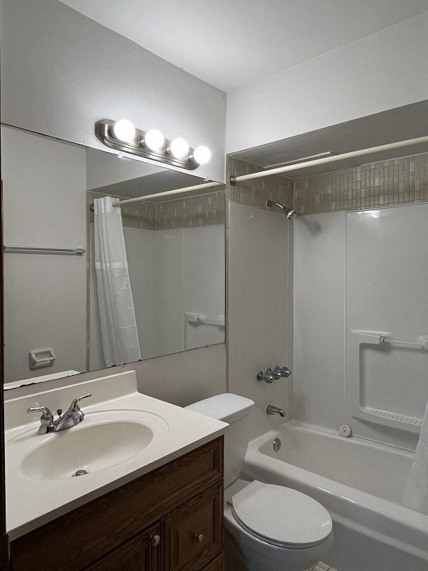 A white toilet is in a bathroom with a sink and mirror.