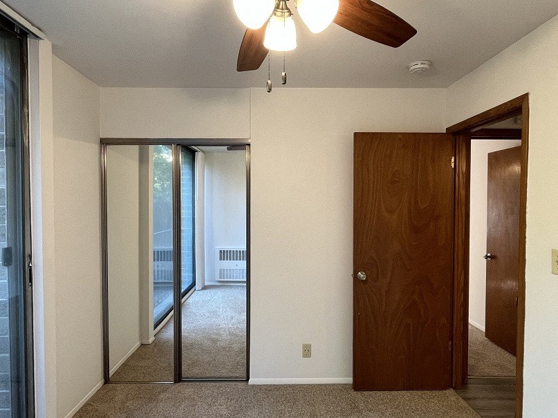 A room with a ceiling fan and a brown door.