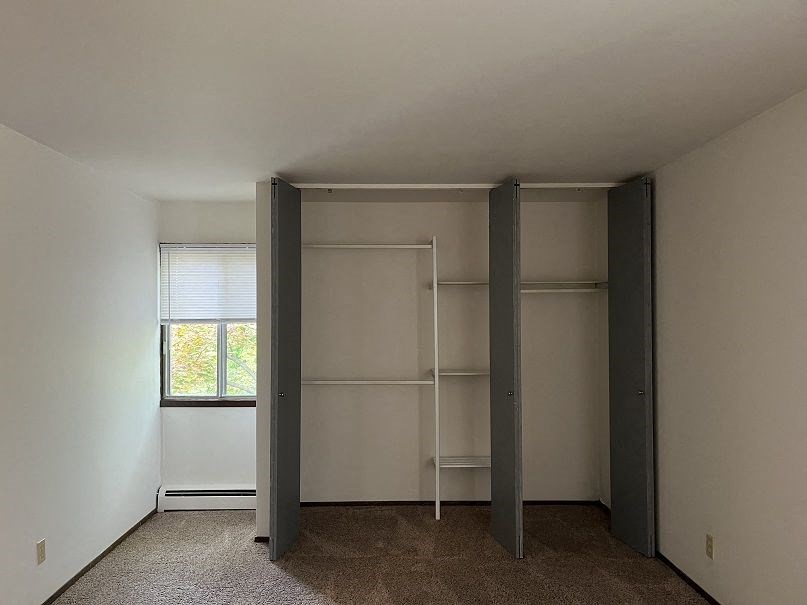 A room with a window and a carpeted floor.