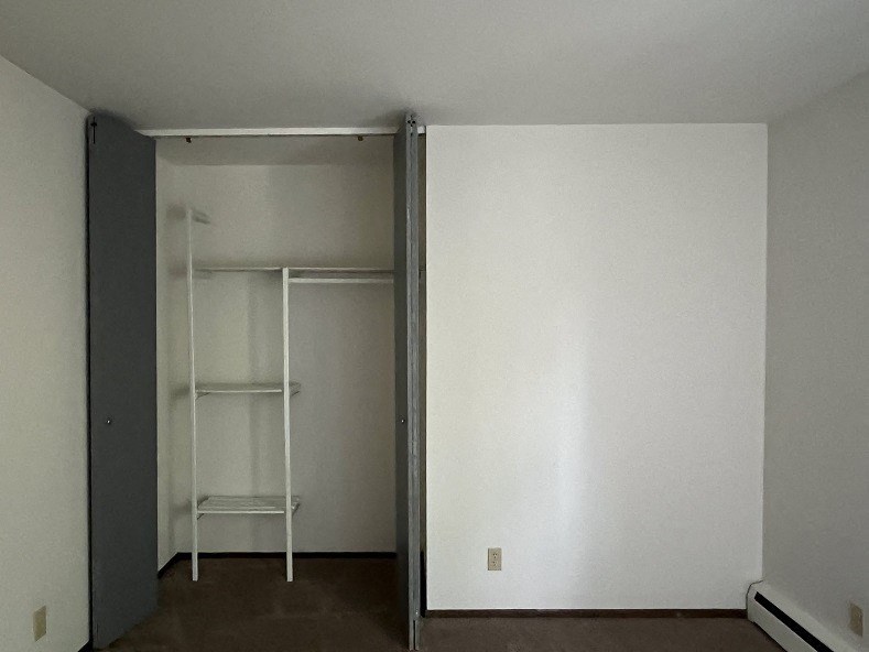 A white shelving unit sits in a room with white walls.
