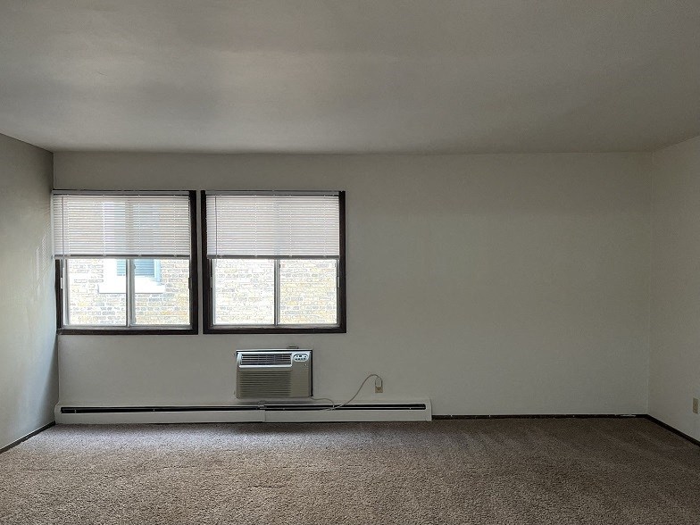 A room with a window and a wall-mounted air conditioner unit.
