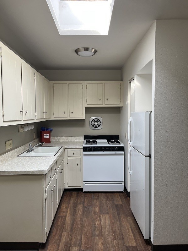 A kitchen with white cabinets and a white fridge.