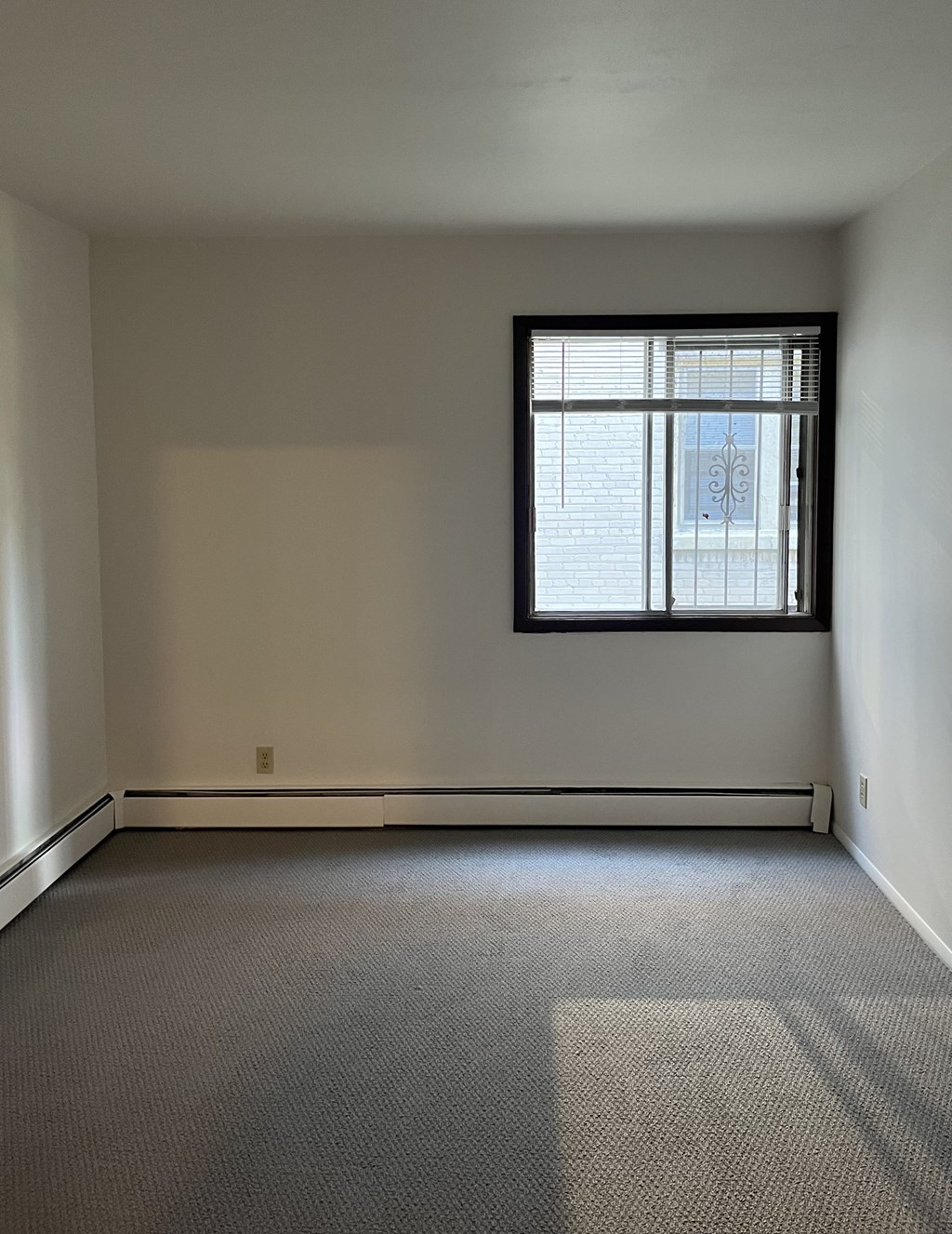 A room with a window and a carpet on the floor.