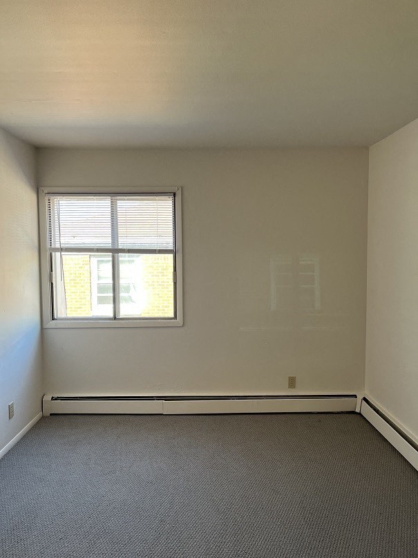 A room with a window and a carpeted floor.