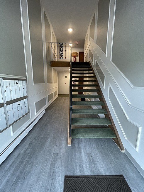 a hallway with stairs and white walls and wood floors