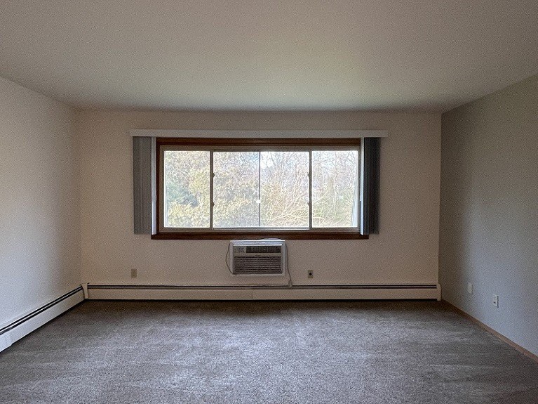 an empty living room with a window and a heater