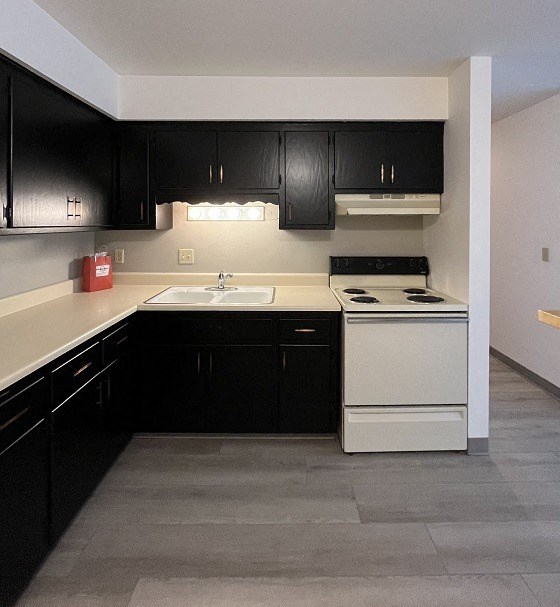 an empty kitchen with black cabinets and white appliances