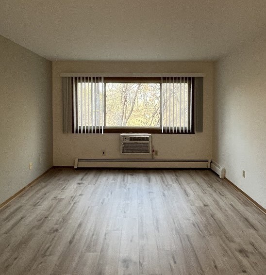 an empty living room with a window and wooden floors
