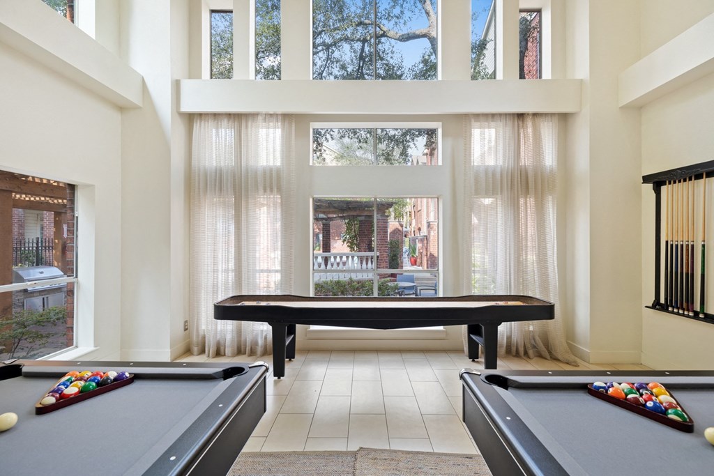 a game room with a pool table and ping pong table in front of a large window