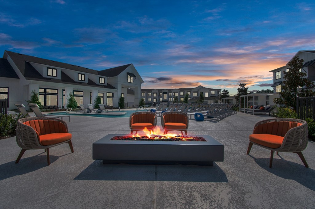 a fire pit in the middle of a patio with chairs around it