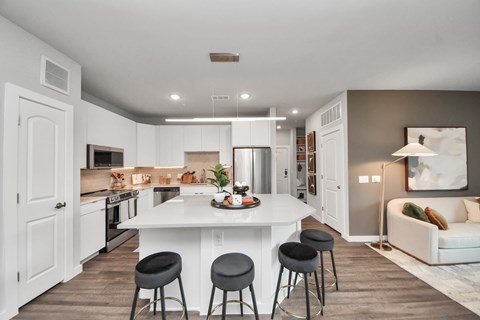 A modern kitchen with a white island and bar stools.