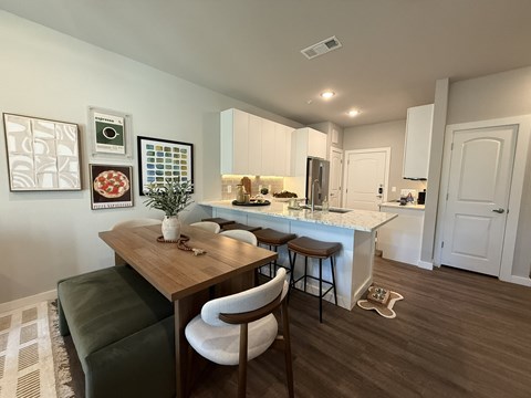 A kitchen with a table and chairs in the foreground and a fridge in the background.