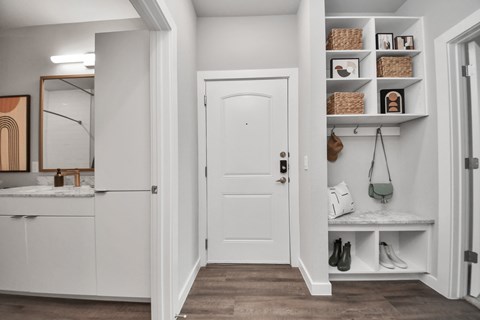 A white door is in a hallway with a shelf above it.