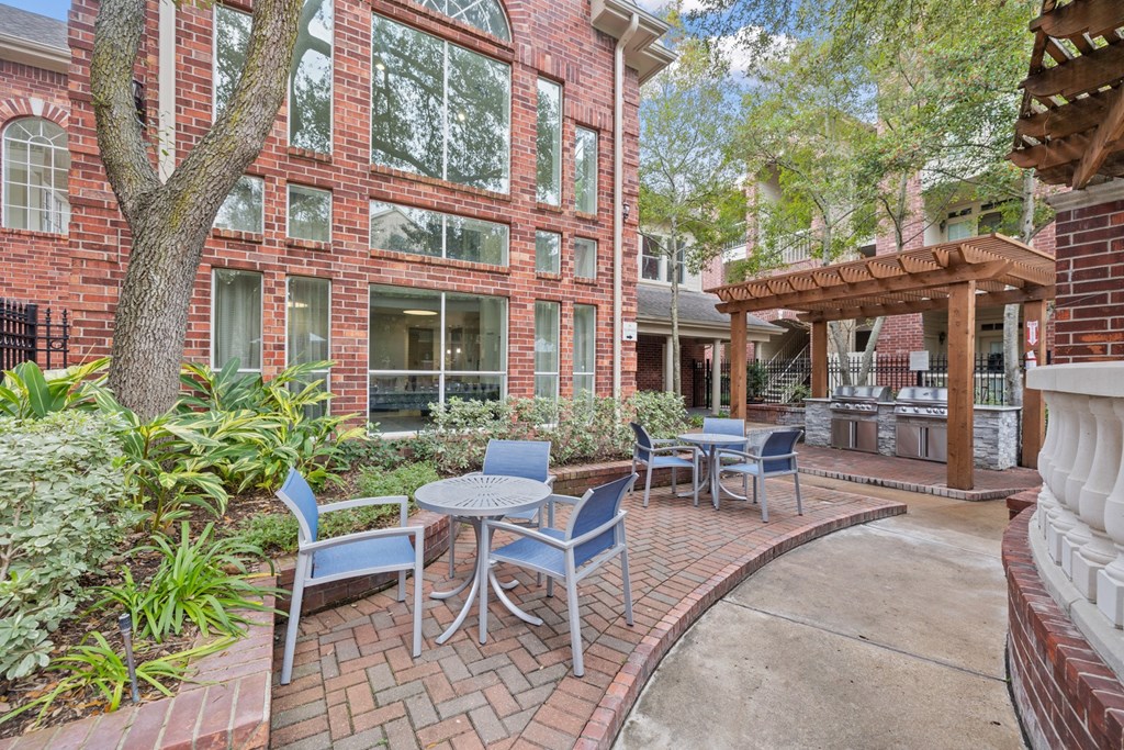 A patio with tables and chairs near outdoor grills