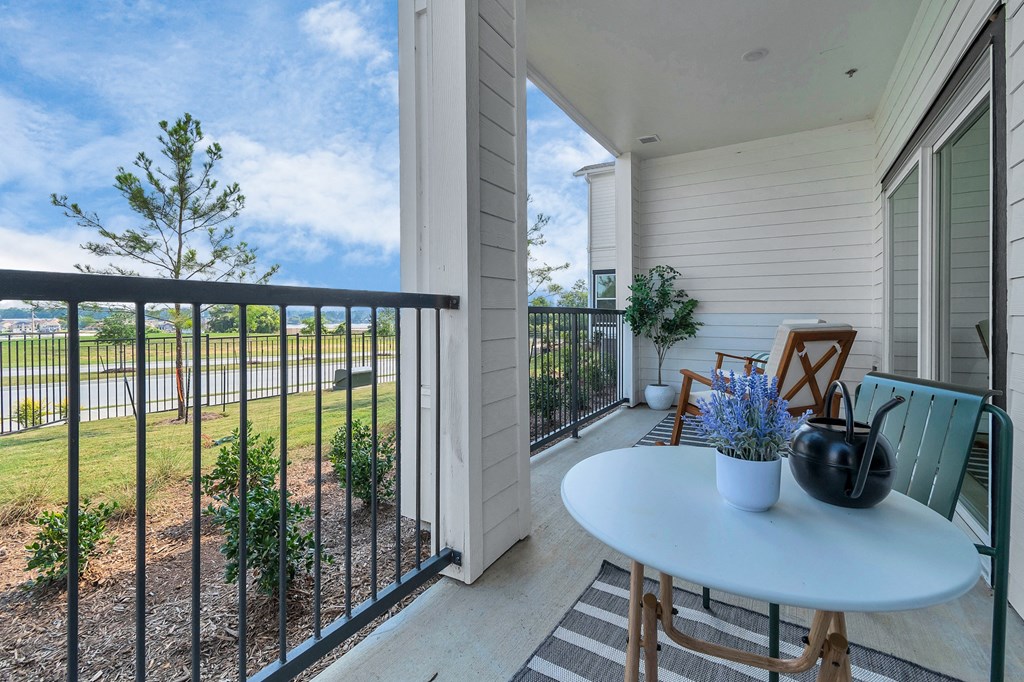 a balcony with a table and chairs and a view of a yard and a house