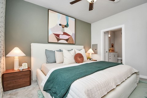 Bedroom with ceiling fan and the door open to the bathroom