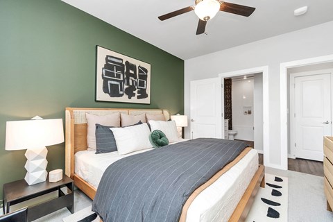 Apartment bedroom with ceiling fan and door open to a bathroom