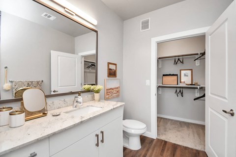 Bathroom with door open to a closet with shelves