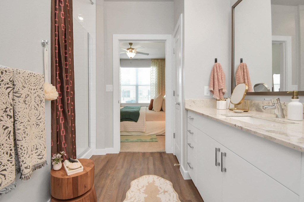 a bathroom with a sink and a mirror and a bedroom with a bed