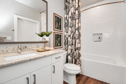 A bathroom with vanity cabinet, custom framed mirror, and soaking tub
