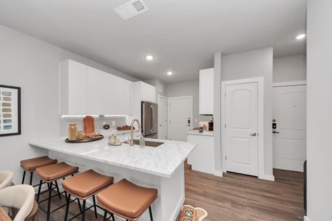 A kitchen with white cabinets and a marble countertop.