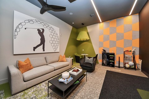 A living room with a couch, a coffee table, and a painting of a person playing golf.