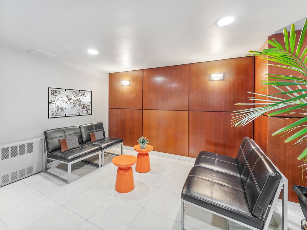 building lobby with black leather couches and orange stools