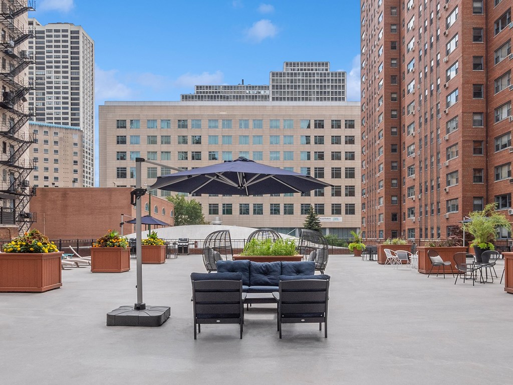 a seating area with couches and chairs on a roof top with a view of the city