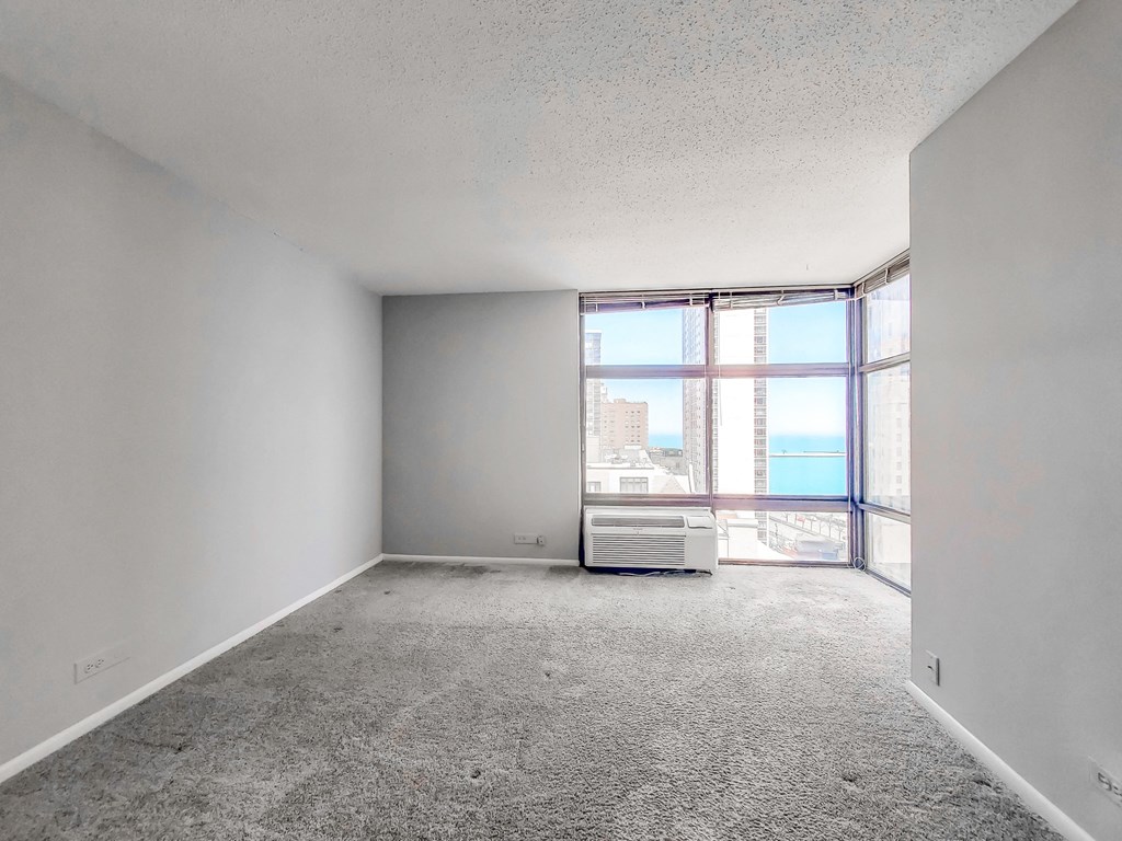 an empty room with a large window and an air conditioner