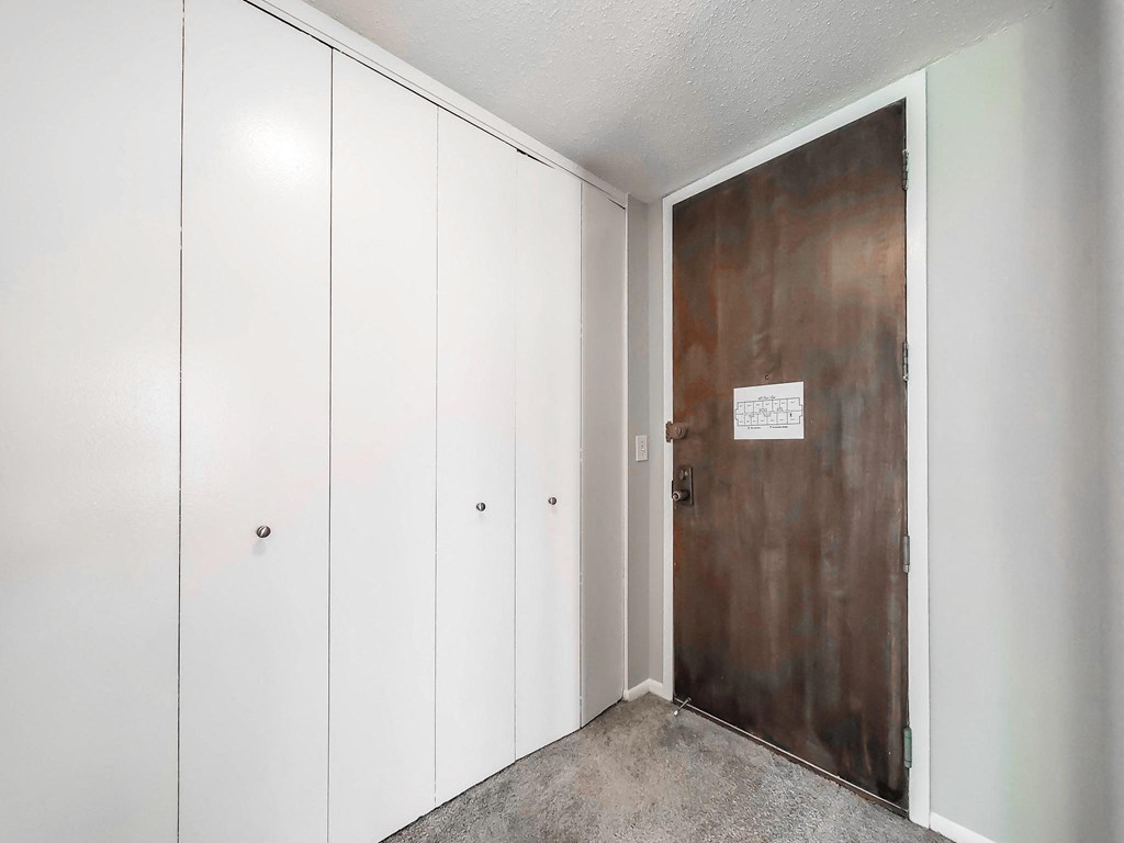 a bedroom with a medium sized white wardrobe and a large metal door