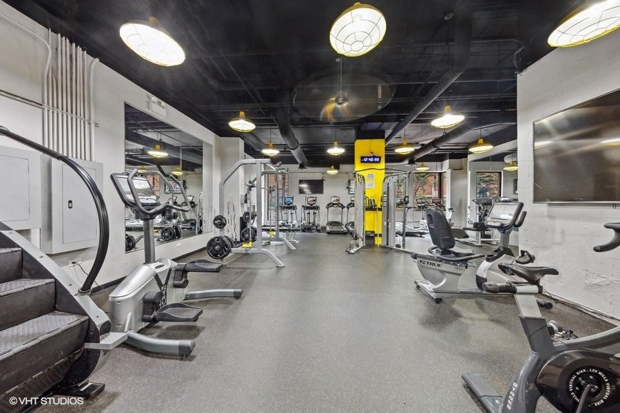 a gym with weights and cardio equipment on the floor and a wall mounted tv