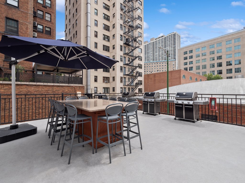 a patio with a table and chairs and a grill