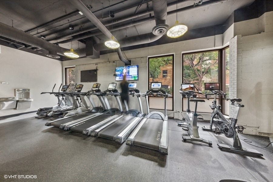 a gym with cardio equipment and windows in a building