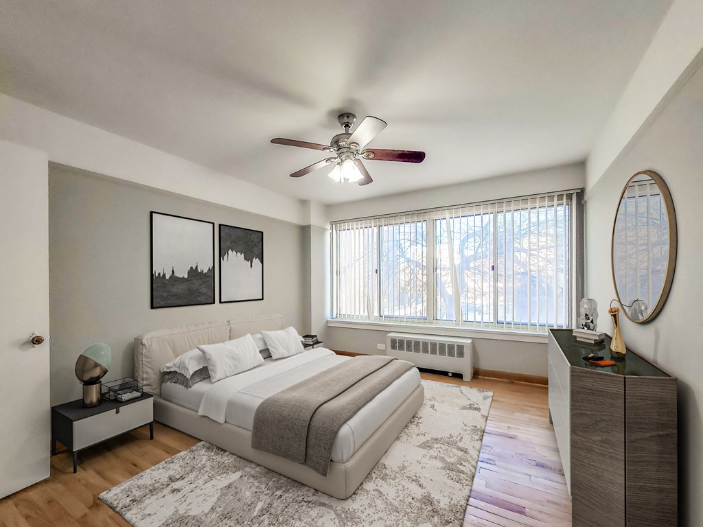 a bedroom with a large window and a ceiling fan