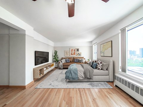 Bright studio with bed, sofa, TV and city views at Clarendon Shores Apartments in Uptown Chicago.