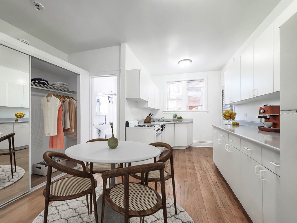 a small kitchen with white cabinets and white countertops and a small white table with two chairs