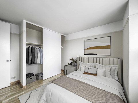 Staged bedroom with queen bed, nightstand, and open closet at Buena Shores Apartments in Buena Park Chicago.