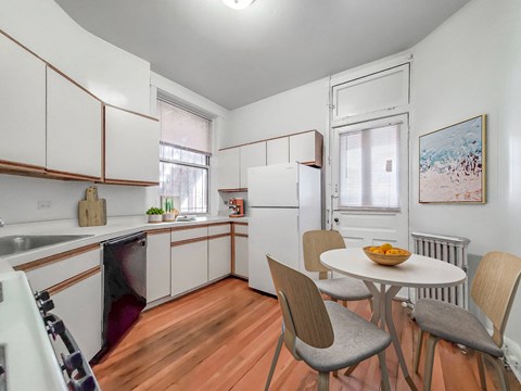 a kitchen with white cabinets and a table and chairs