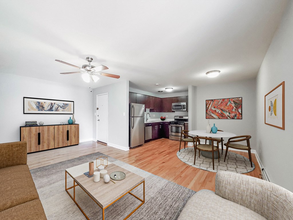 a living room with a couch a table and a chair and a kitchen with a stove and