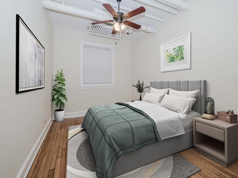 Berteau Manor apartment bedroom in Lakeview Chicago with queen bed, gray headboard, nightstand, potted plant.
