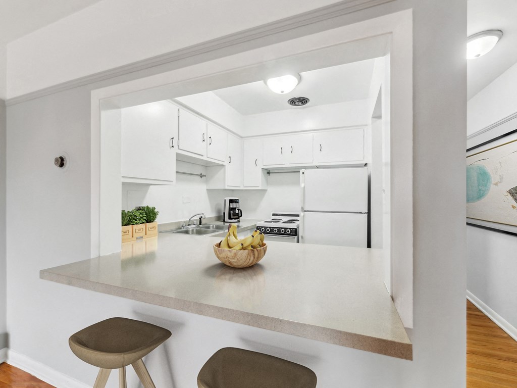 a kitchen with white cabinets and a white counter top with a bowl of fruit on it