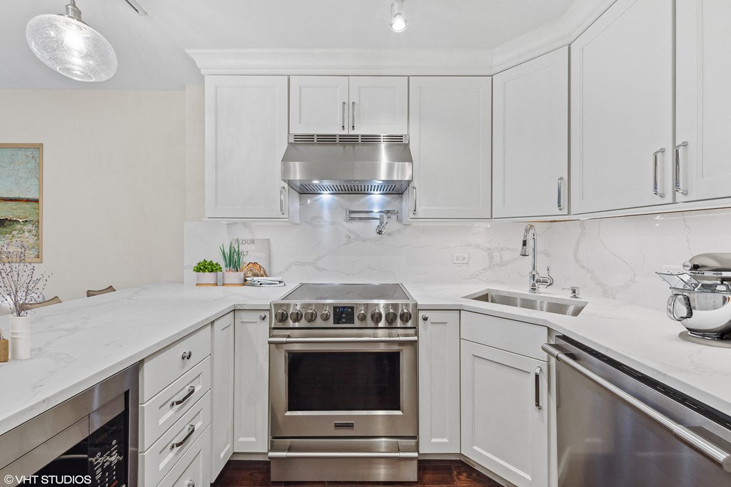 a white kitchen with stainless steel appliances and white cabinets